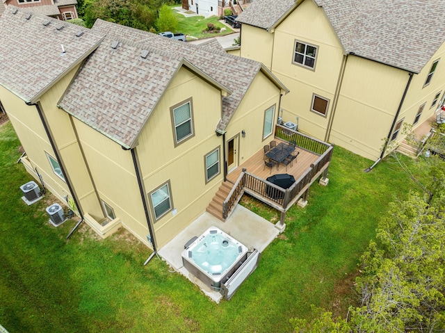 rear view of house with a yard, roof with shingles, an outdoor hot tub, and a deck