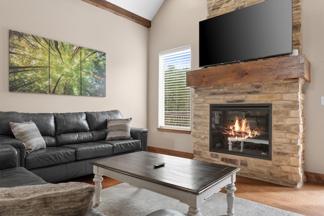 living area with a stone fireplace, lofted ceiling, and wood finished floors