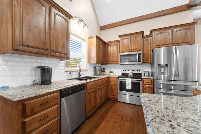 kitchen with vaulted ceiling, a sink, stainless steel appliances, dark wood-style flooring, and light stone countertops