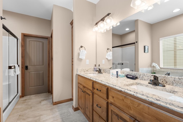 bathroom with double vanity, a shower stall, and a sink
