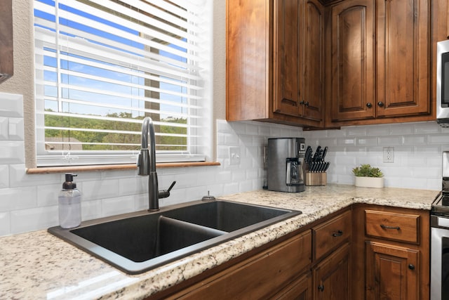 kitchen featuring light stone countertops, backsplash, and sink