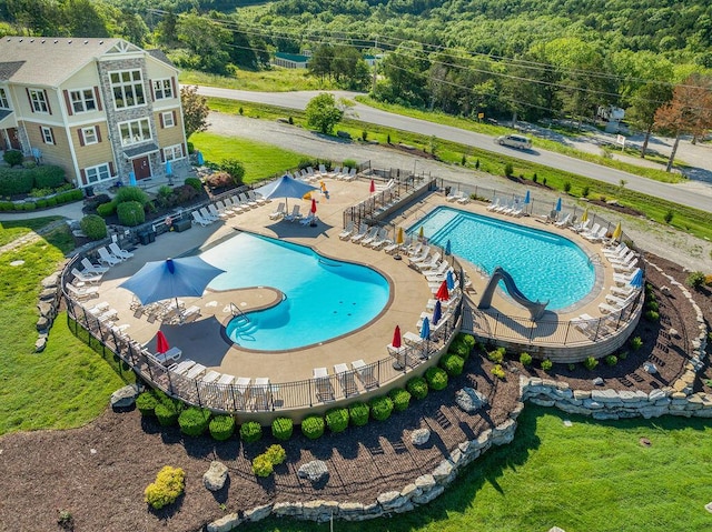 pool featuring a view of trees and a patio
