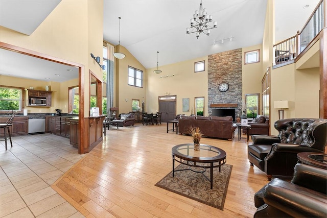 living area featuring light wood-style floors, a fireplace, high vaulted ceiling, and a notable chandelier
