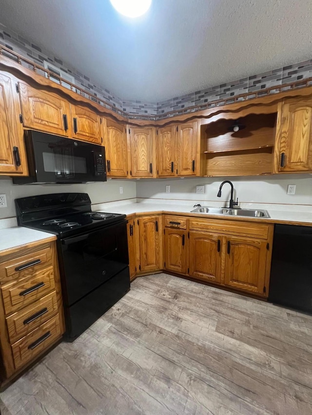 kitchen with light wood-type flooring, sink, and black appliances