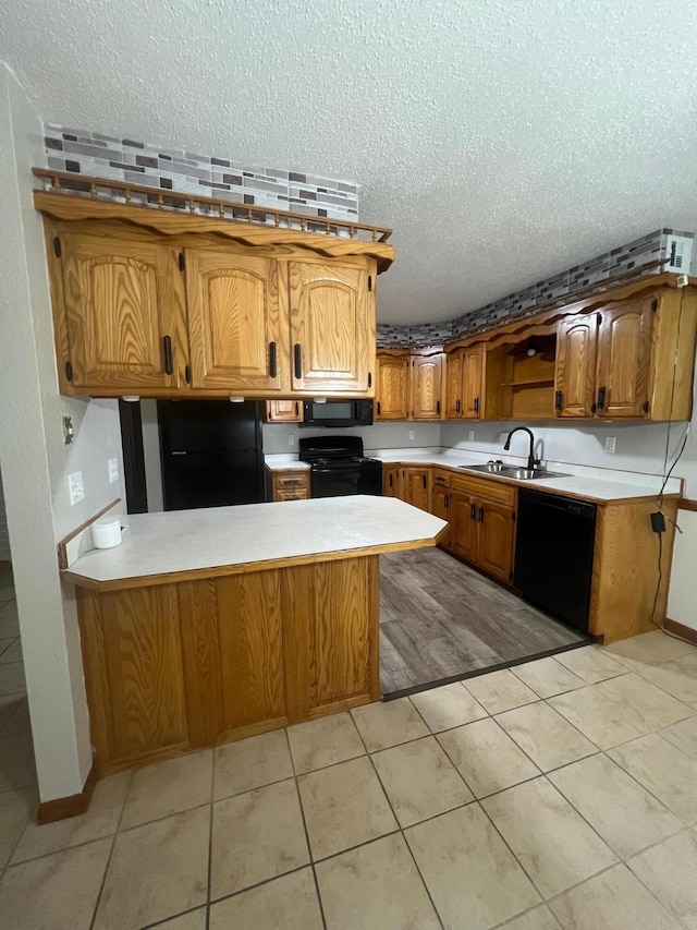 kitchen with kitchen peninsula, black appliances, sink, and a textured ceiling