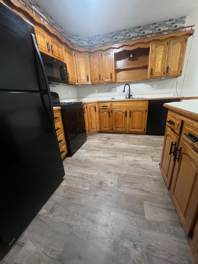 kitchen with black appliances, sink, and light hardwood / wood-style flooring