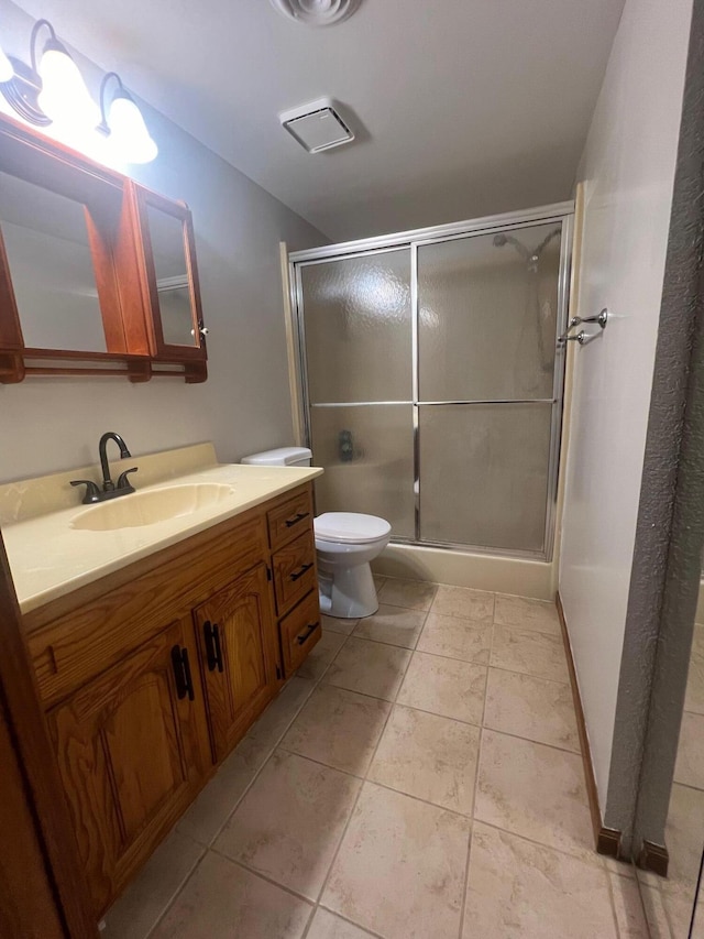 bathroom featuring tile patterned floors, a shower with shower door, vanity, and toilet