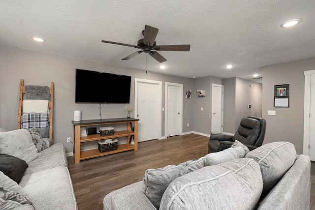 living room with dark wood-type flooring, ceiling fan, and a textured ceiling