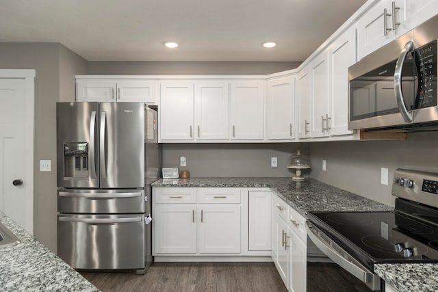 kitchen featuring light stone countertops, appliances with stainless steel finishes, dark hardwood / wood-style floors, and white cabinets