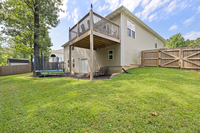 back of property featuring a trampoline, a lawn, and a deck