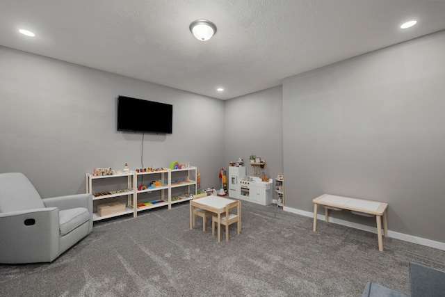 rec room featuring a textured ceiling and dark carpet