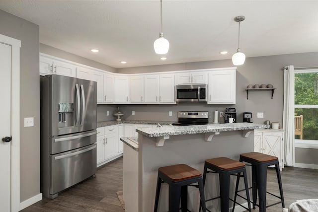 kitchen with a breakfast bar, white cabinetry, decorative light fixtures, stainless steel appliances, and light stone countertops