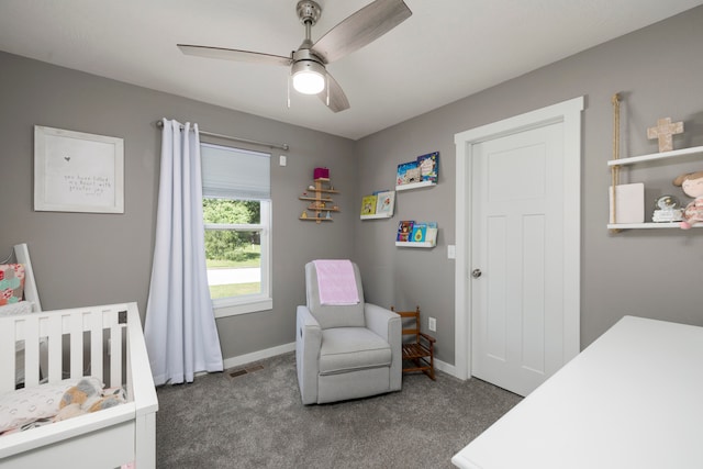 bedroom with ceiling fan, a crib, and dark colored carpet