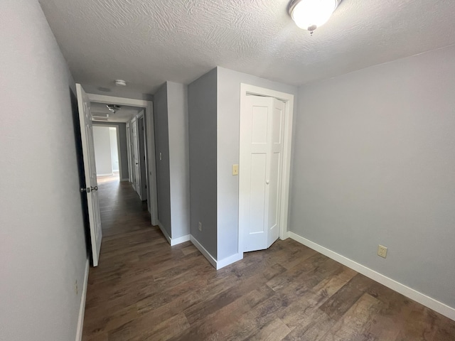 corridor featuring a textured ceiling and dark hardwood / wood-style floors