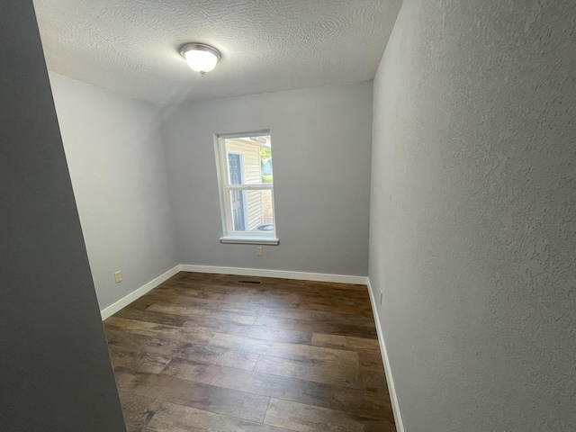 unfurnished room featuring a textured ceiling and dark hardwood / wood-style floors