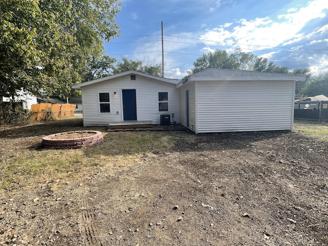 rear view of property with a lawn, central AC unit, and an outdoor fire pit