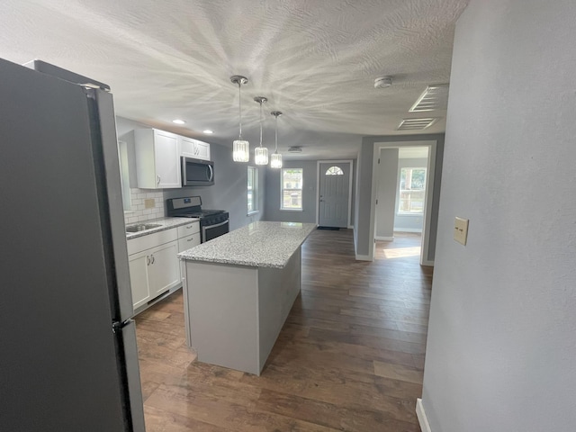 kitchen featuring decorative backsplash, appliances with stainless steel finishes, a center island, and white cabinetry