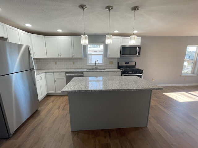 kitchen featuring white cabinets, appliances with stainless steel finishes, a kitchen island, and sink