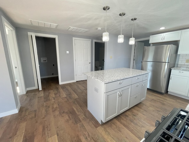 kitchen featuring stainless steel refrigerator, white cabinetry, light stone counters, pendant lighting, and a kitchen island