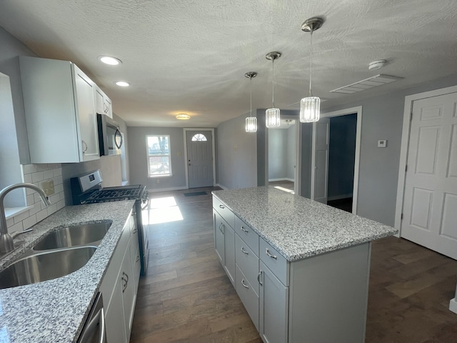 kitchen featuring stainless steel appliances, dark wood-type flooring, sink, pendant lighting, and a center island