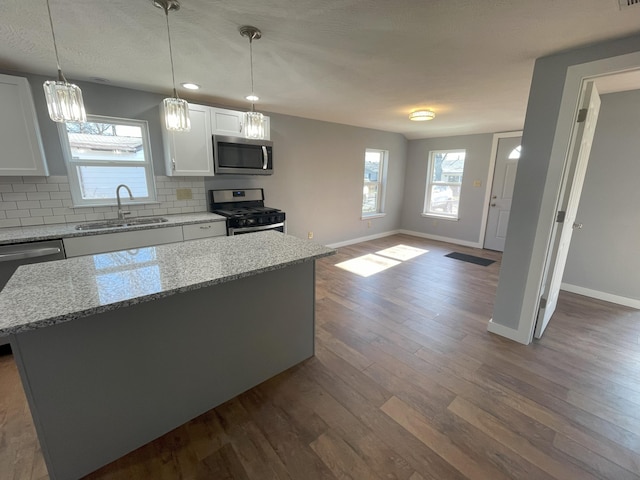 kitchen with a center island, sink, light stone countertops, white cabinetry, and stainless steel appliances