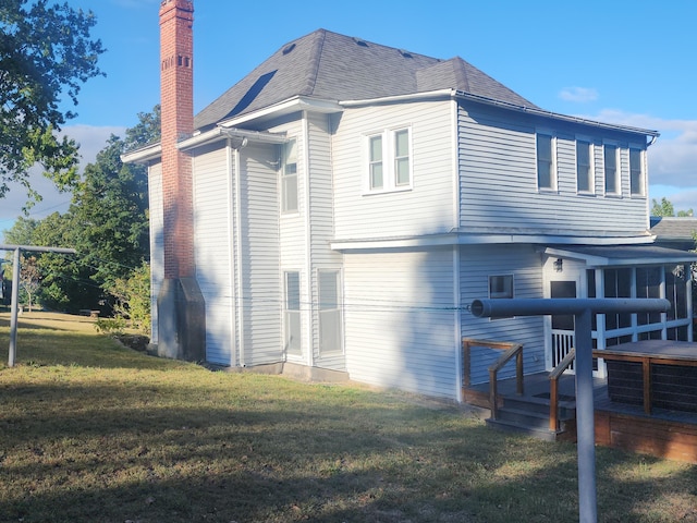 back of property featuring a wooden deck and a lawn