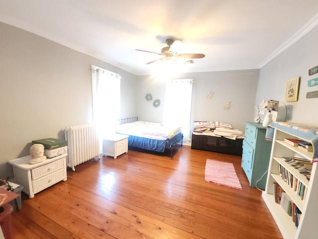 bedroom with wood-type flooring, ceiling fan, crown molding, and radiator