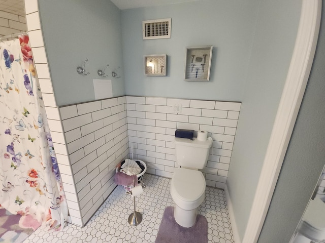 bathroom featuring tile walls, walk in shower, tile patterned floors, and toilet