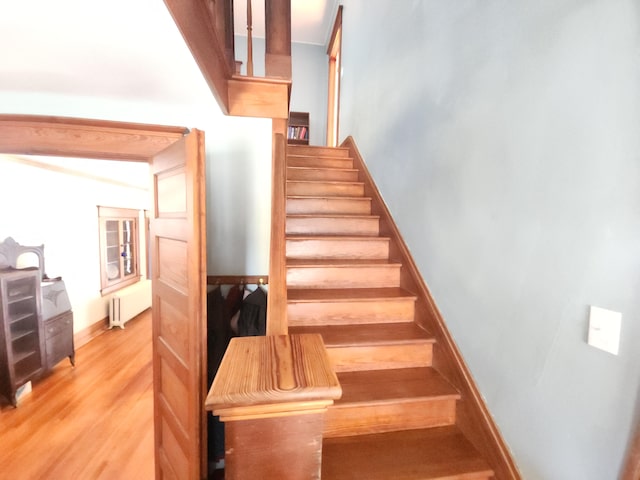 staircase featuring wood-type flooring and radiator heating unit