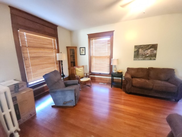 living room featuring wood-type flooring, radiator heating unit, and ceiling fan