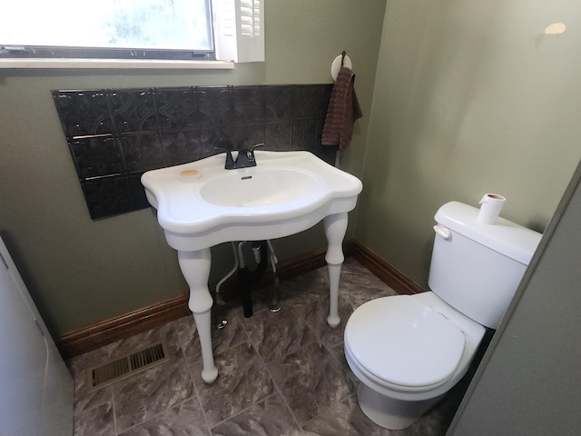 bathroom featuring toilet and backsplash