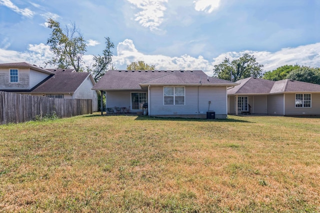 rear view of property featuring fence and a yard