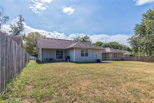 back of house with a fenced backyard and a yard