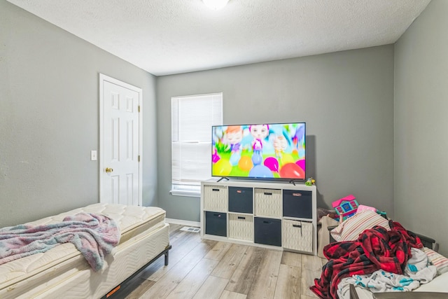 bedroom with baseboards, wood finished floors, and a textured ceiling