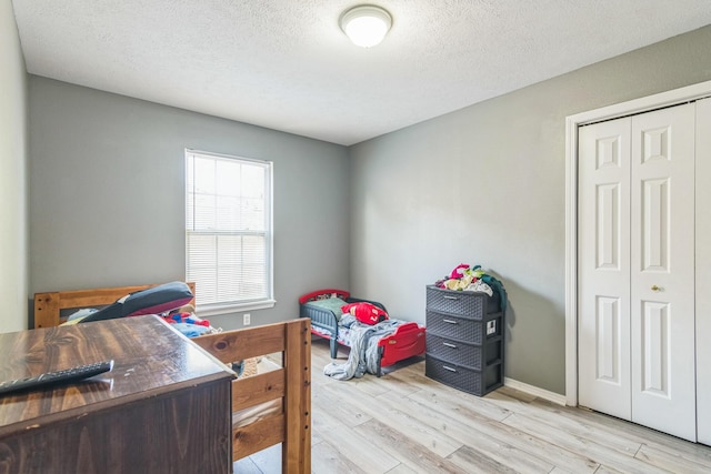bedroom featuring a textured ceiling, light wood finished floors, and a closet
