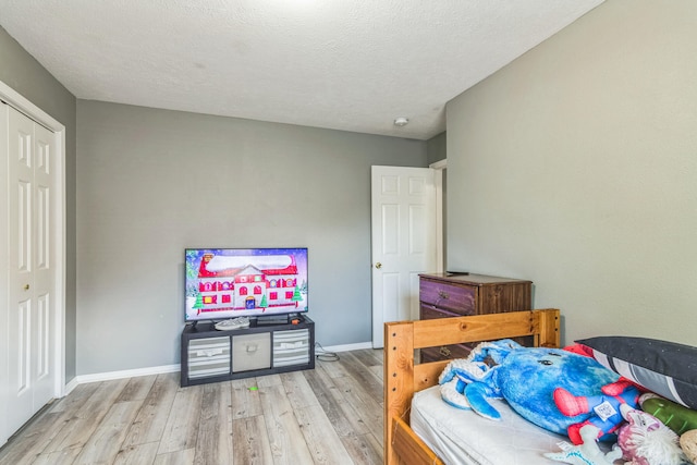 bedroom with a textured ceiling, a closet, and light hardwood / wood-style floors