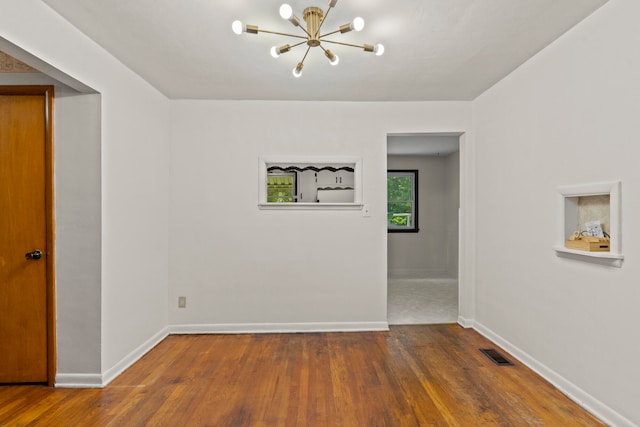 empty room featuring a chandelier and wood-type flooring