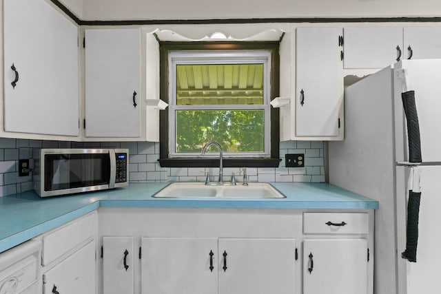 kitchen featuring backsplash, white fridge, sink, and white cabinets