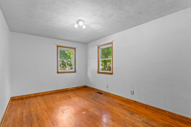 unfurnished room with wood-type flooring and a textured ceiling