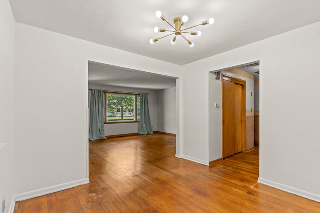 unfurnished room featuring hardwood / wood-style floors and a chandelier