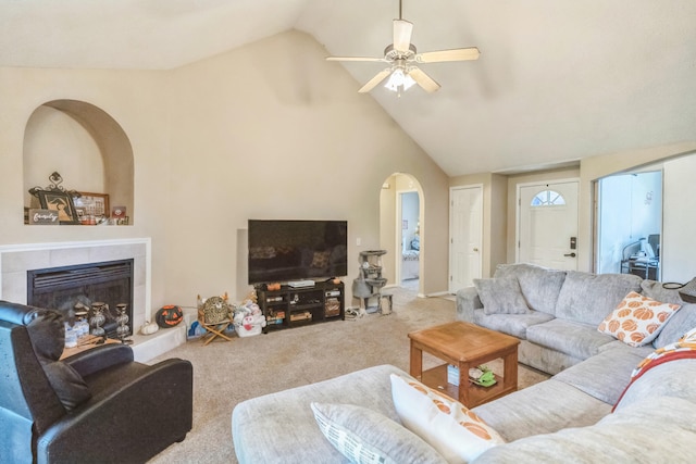 carpeted living room featuring ceiling fan, high vaulted ceiling, and a tiled fireplace