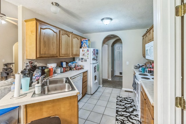 kitchen with white appliances, sink, kitchen peninsula, light tile patterned floors, and a textured ceiling