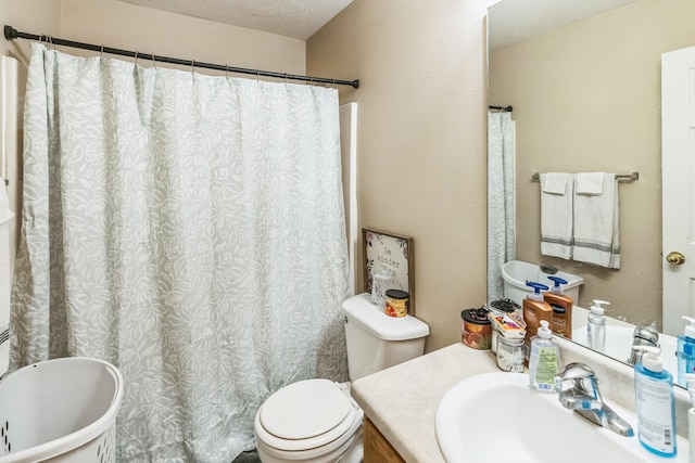 bathroom featuring a bathing tub, vanity, toilet, and a textured ceiling