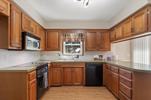 kitchen featuring kitchen peninsula, black appliances, light hardwood / wood-style flooring, and a healthy amount of sunlight