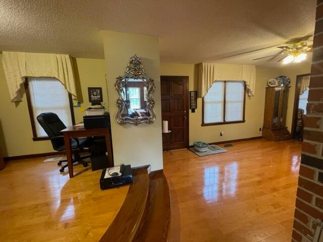 interior space featuring ceiling fan, a textured ceiling, and light hardwood / wood-style floors