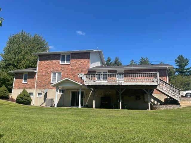 back of property featuring a wooden deck and a lawn