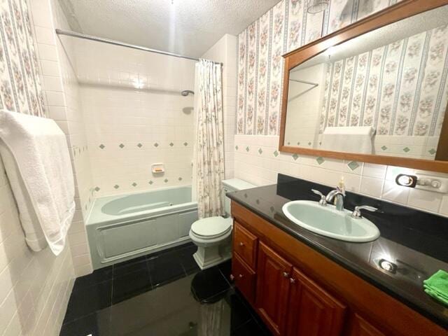 full bathroom with toilet, shower / tub combo, a textured ceiling, tile walls, and vanity