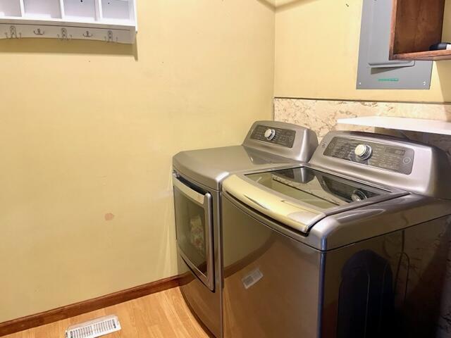 laundry area with washer and clothes dryer and light hardwood / wood-style floors