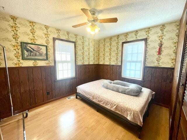 bedroom with ceiling fan, a textured ceiling, and light wood-type flooring