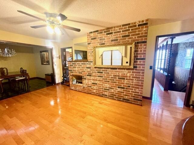 living room with ceiling fan, brick wall, hardwood / wood-style floors, and a textured ceiling